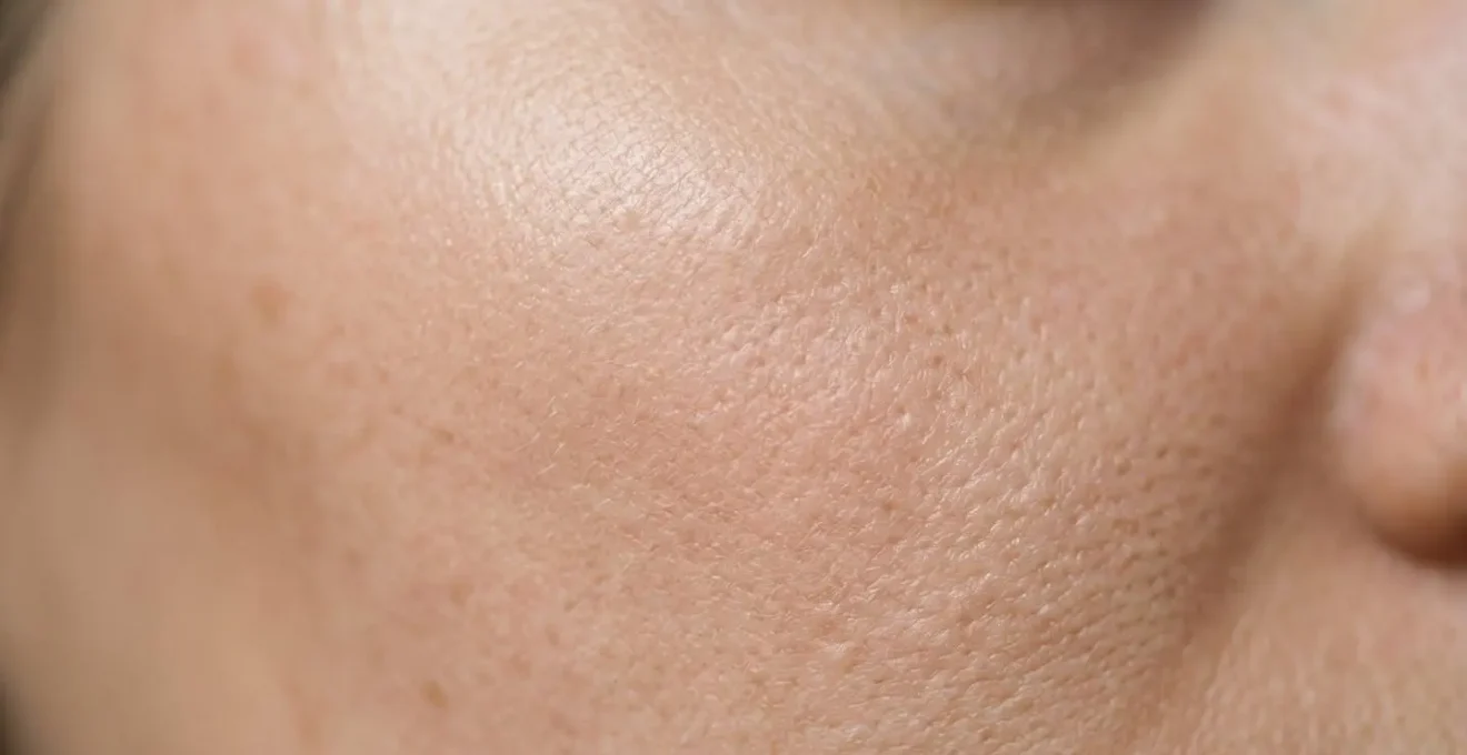 Primo piano dettagliato di pelle del viso con texture affinata e pori minimizzati sotto luce naturale morbida
